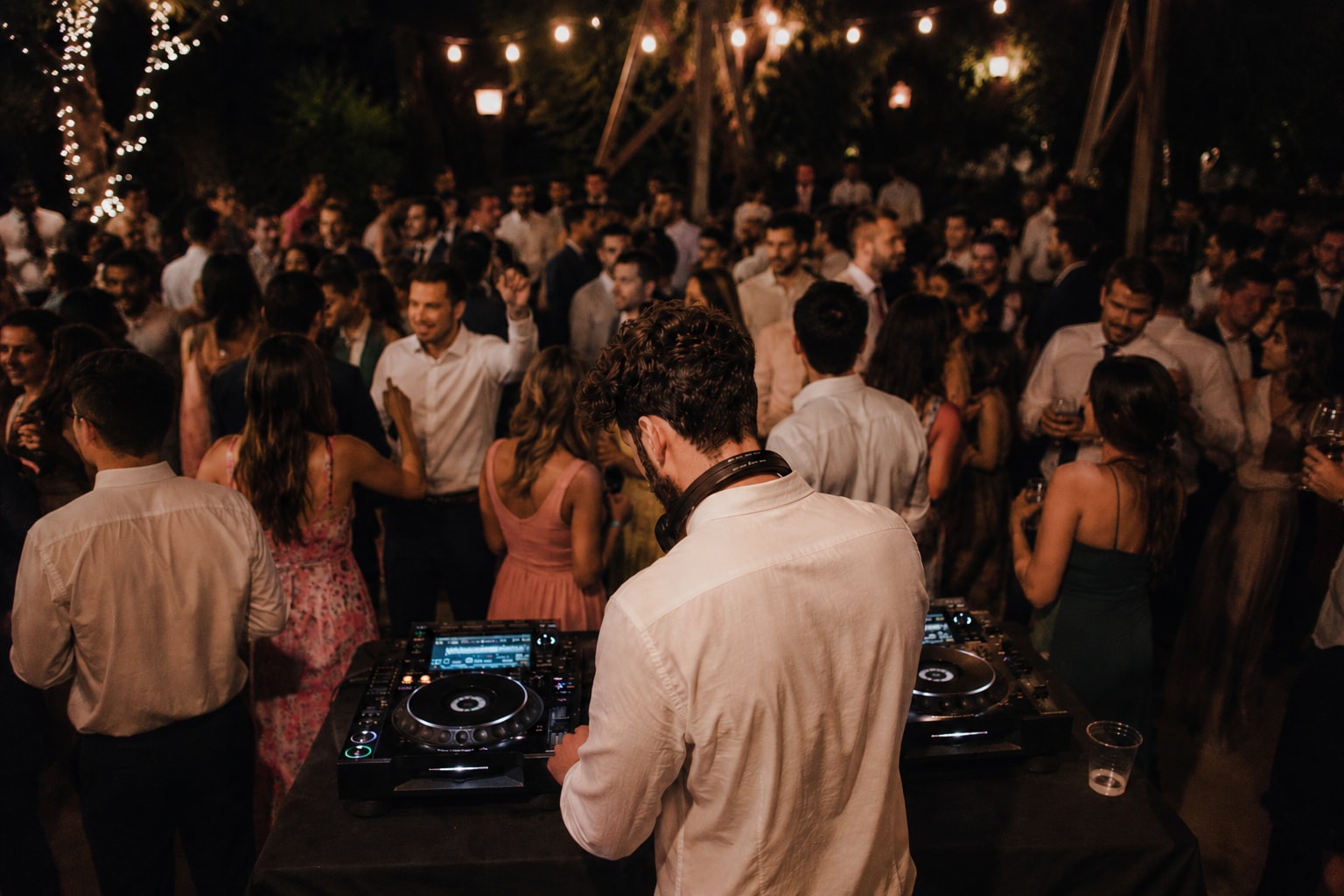 A wedding dancefloor mid-celebration, hands in the air under confetti